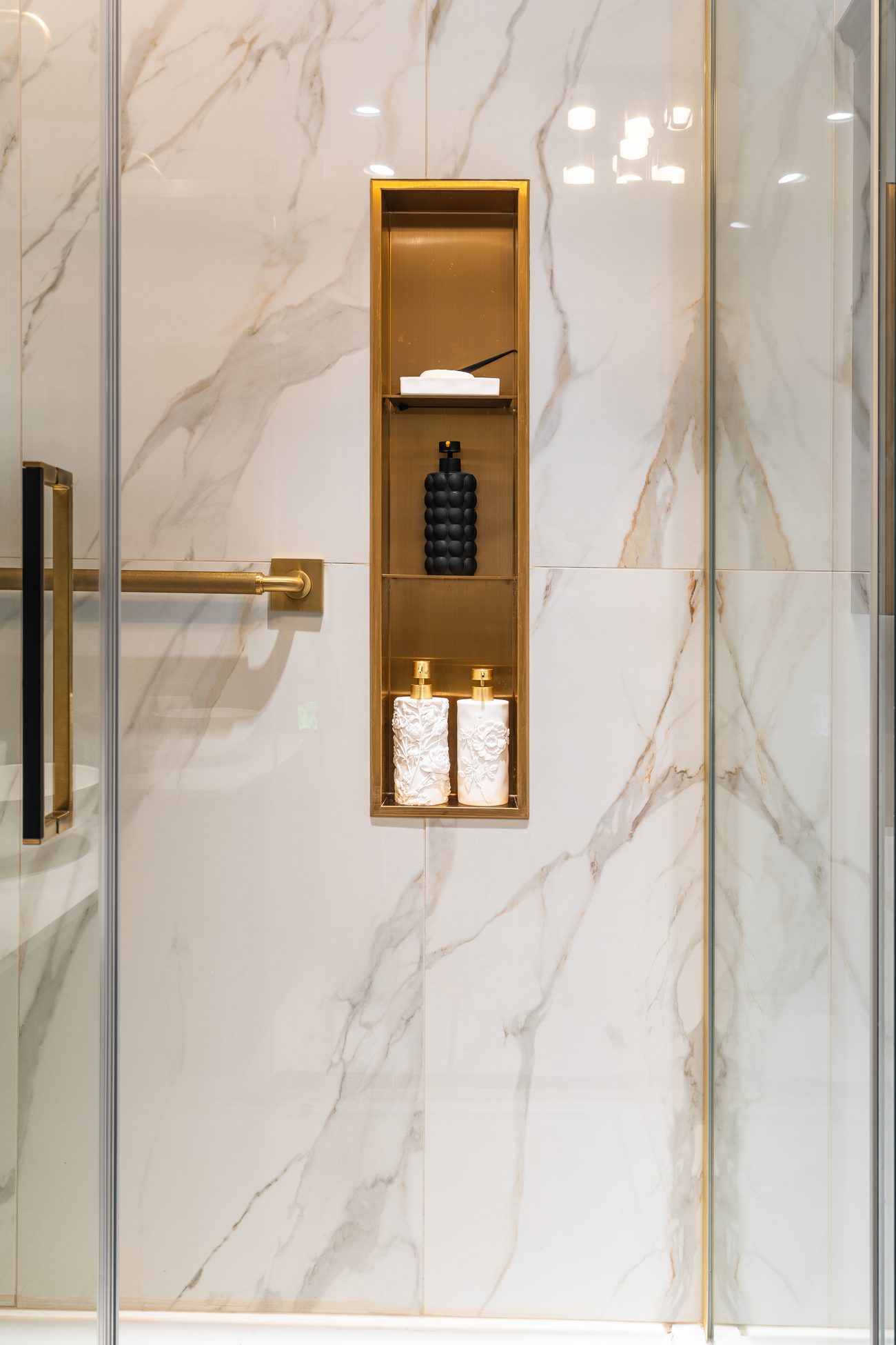 Brass shower niche set into book-matched marble