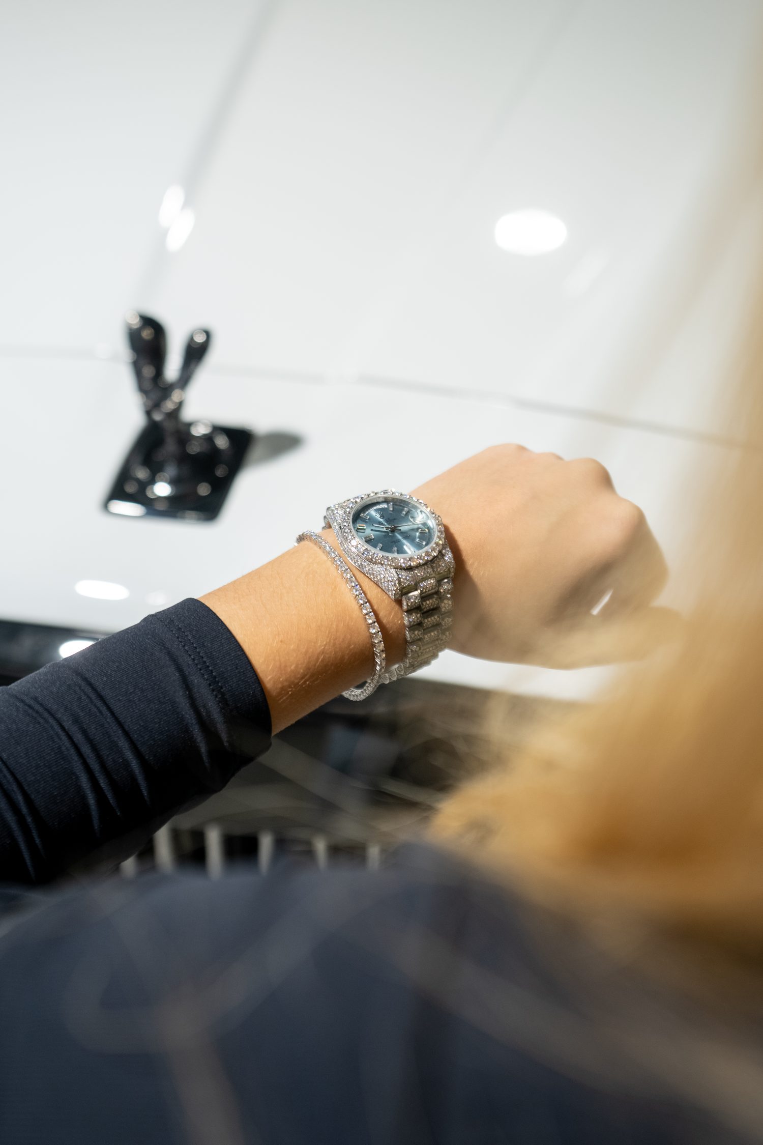 Diamond-set Rolex Day-Date and tennis bracelet, photographed over a Rolls-Royce bonnet