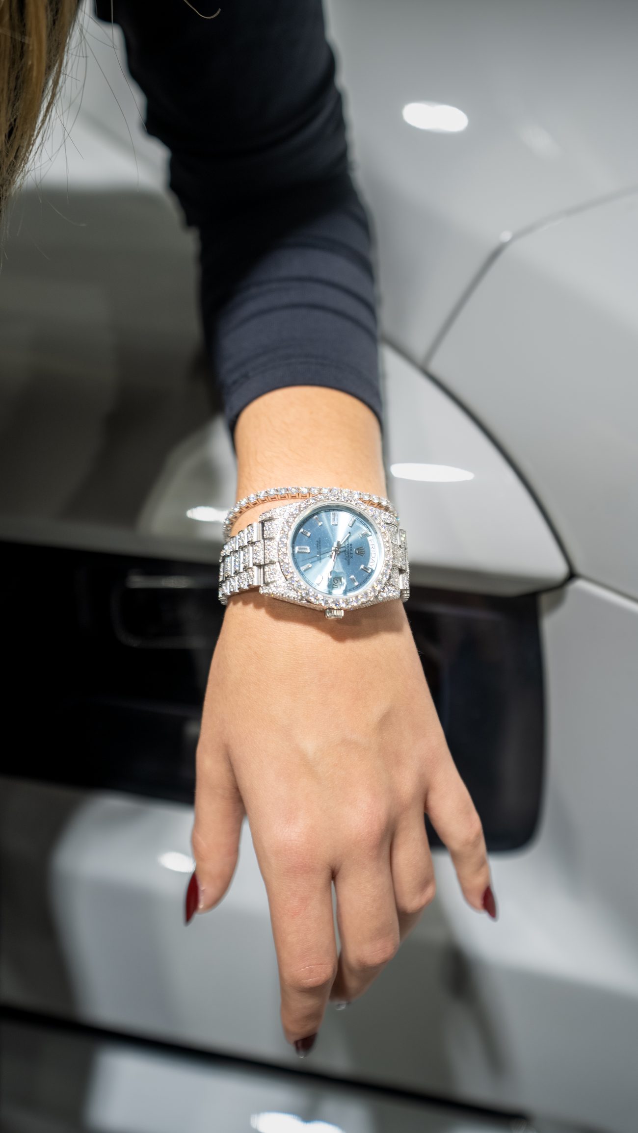 Diamond-set Rolex Day-Date with ice-blue dial, worn against a car